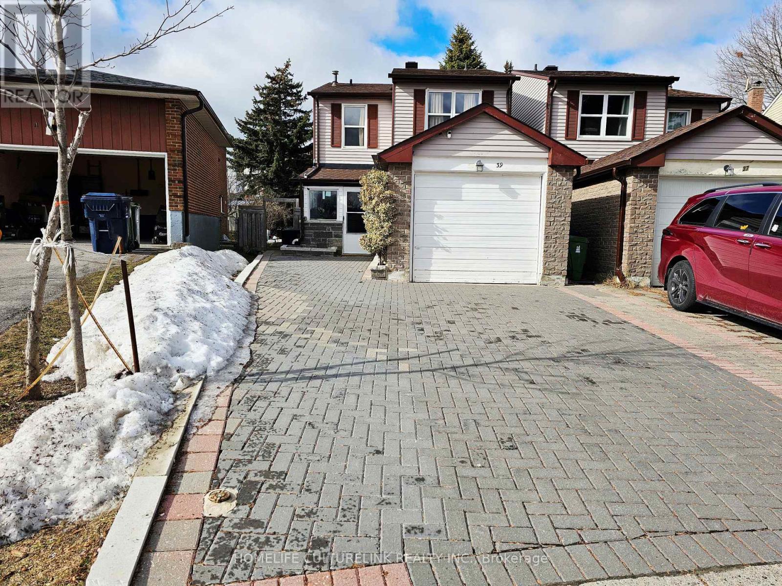 A red car is parked in front of a house with a driveway.