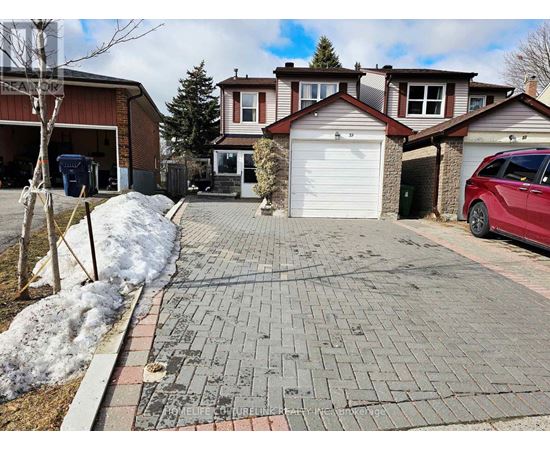A red car is parked in front of a house with a driveway.