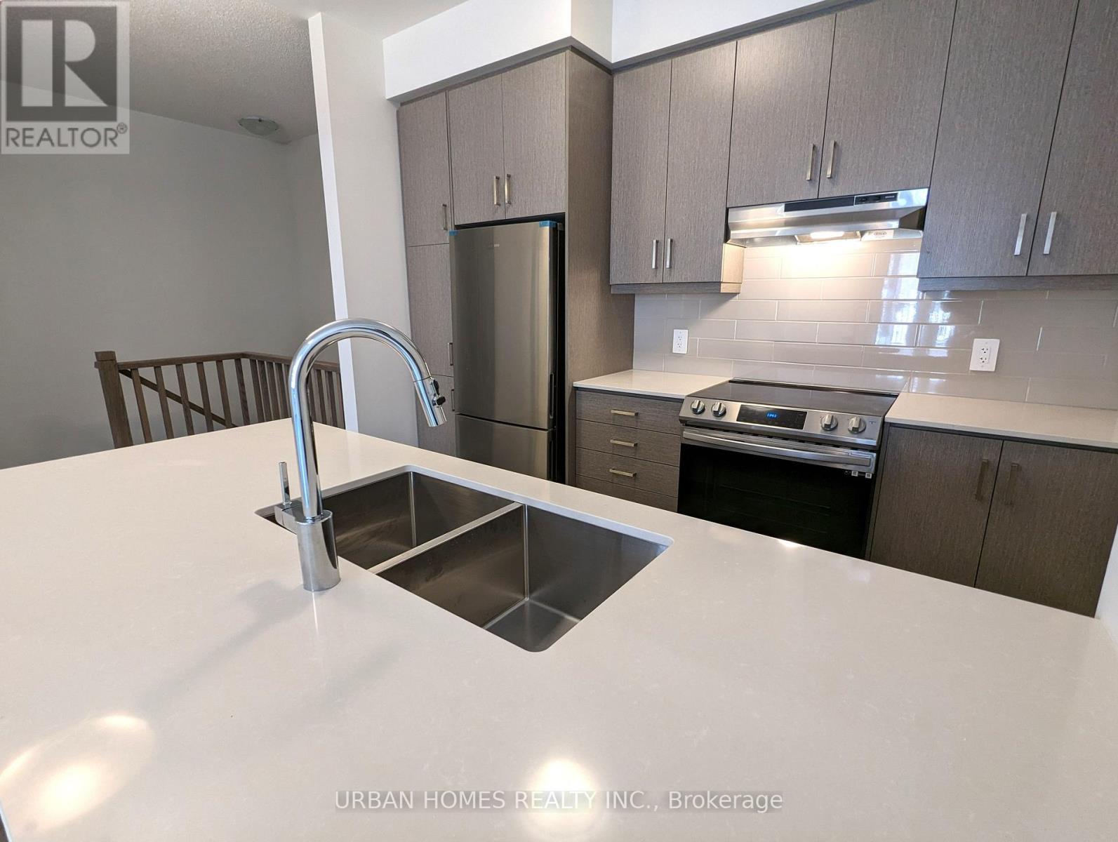 A kitchen with a white counter top and a stainless steel sink.