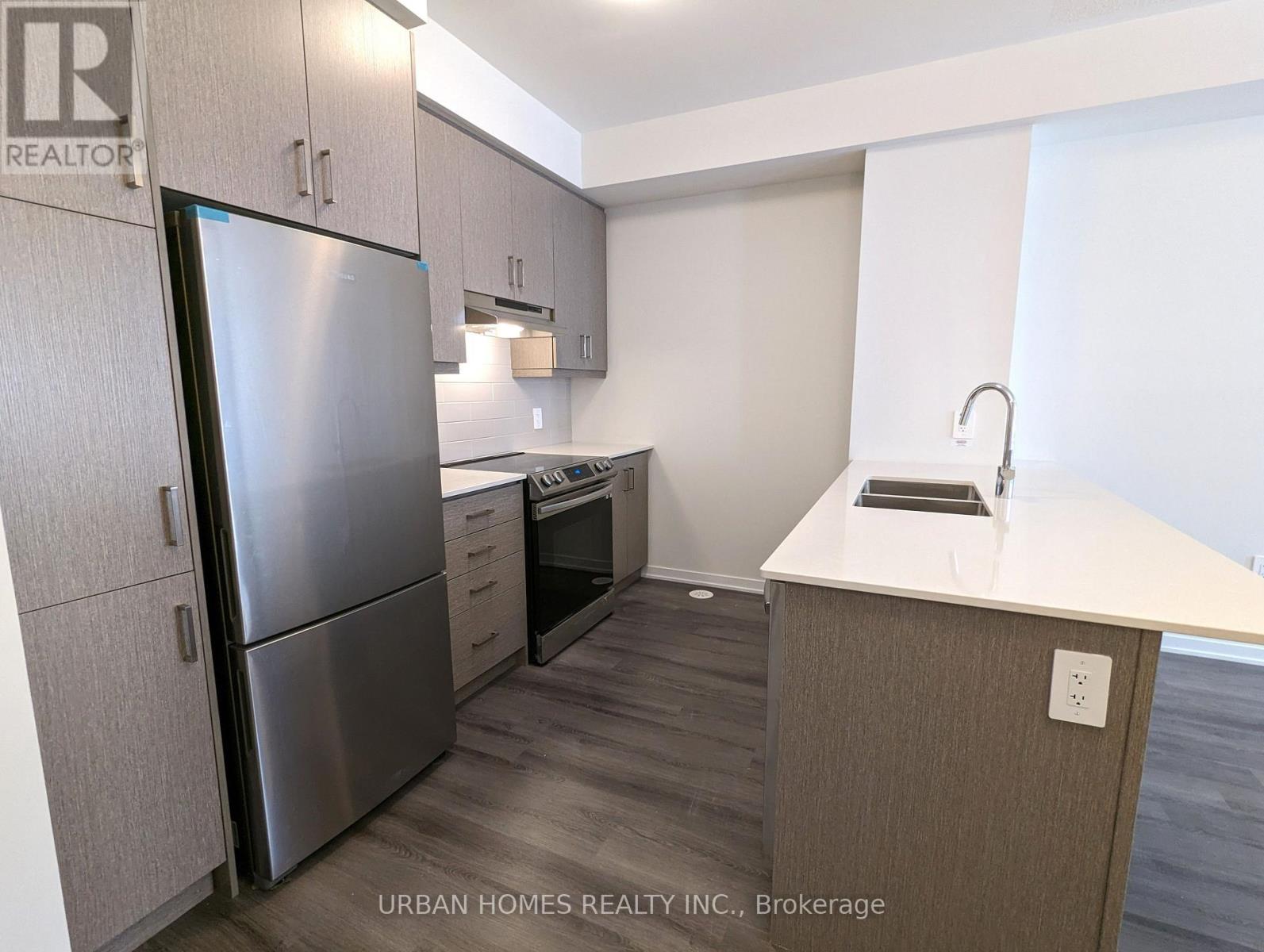A kitchen with a refrigerator, oven, and sink.
