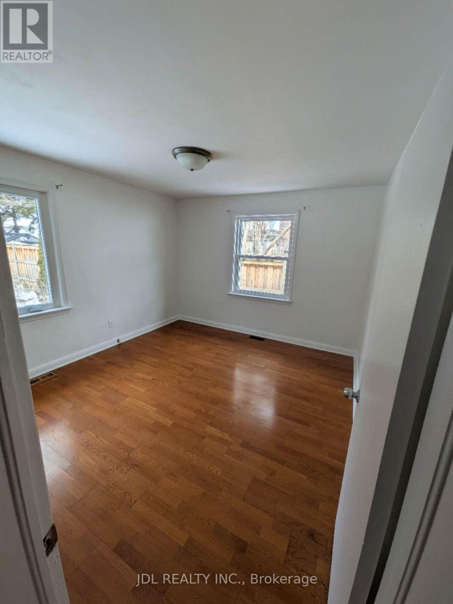 A room with wooden flooring and a window with bars on it.