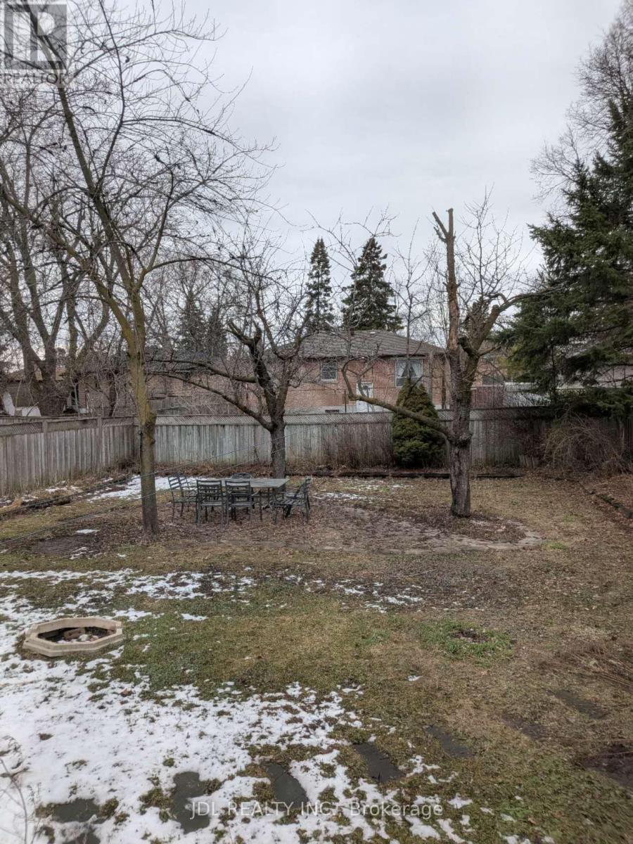 A backyard with a fence, trees, and a fire pit.