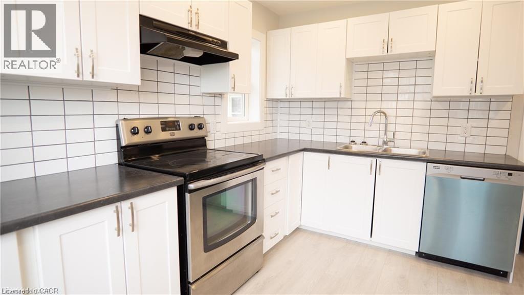 A kitchen with white cabinets and black countertops.