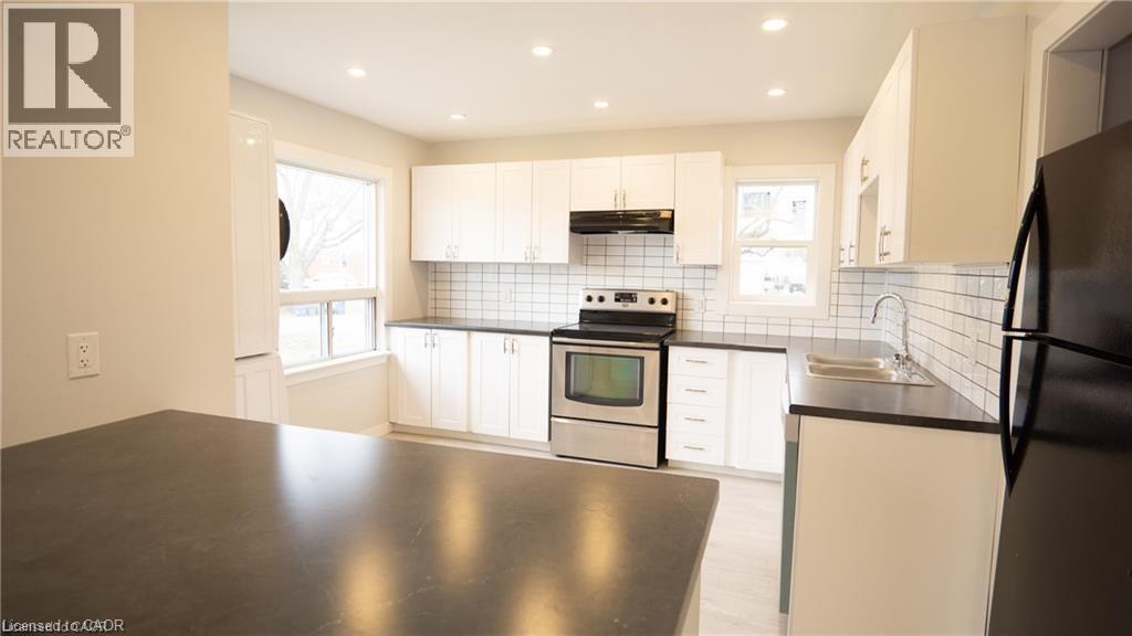A modern kitchen with a black countertop and stainless steel appliances.