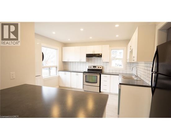 A modern kitchen with a black countertop and stainless steel appliances.