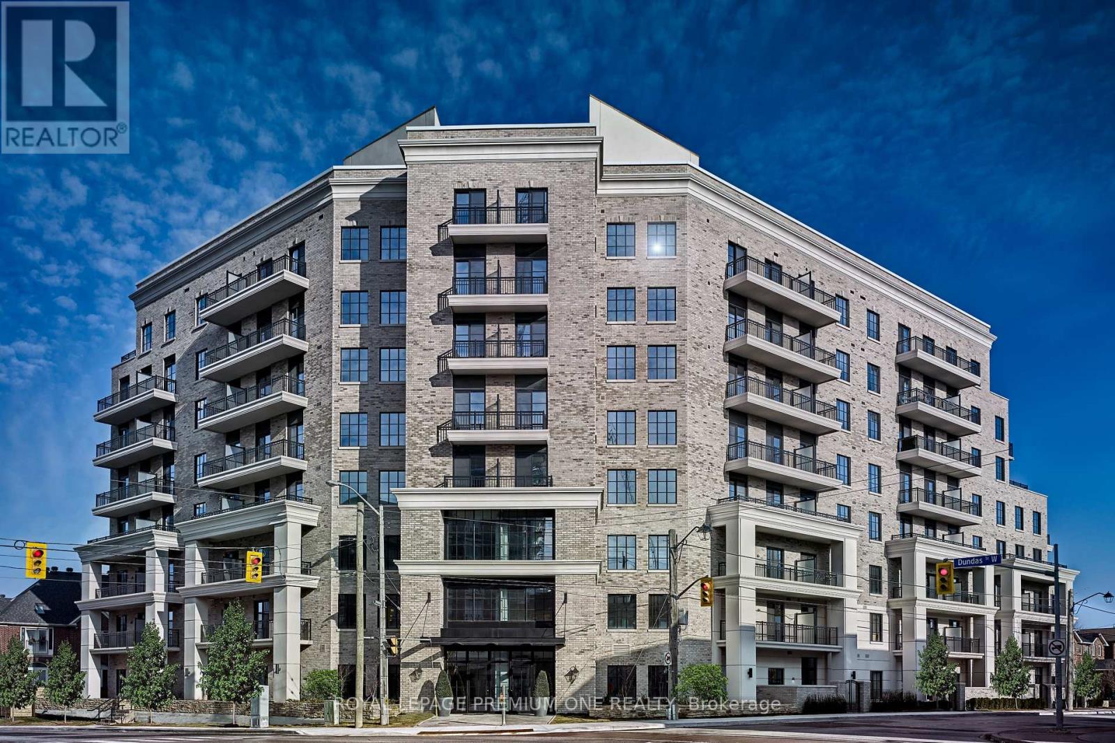 A large, modern apartment building with multiple balconies and a clear blue sky in the background.