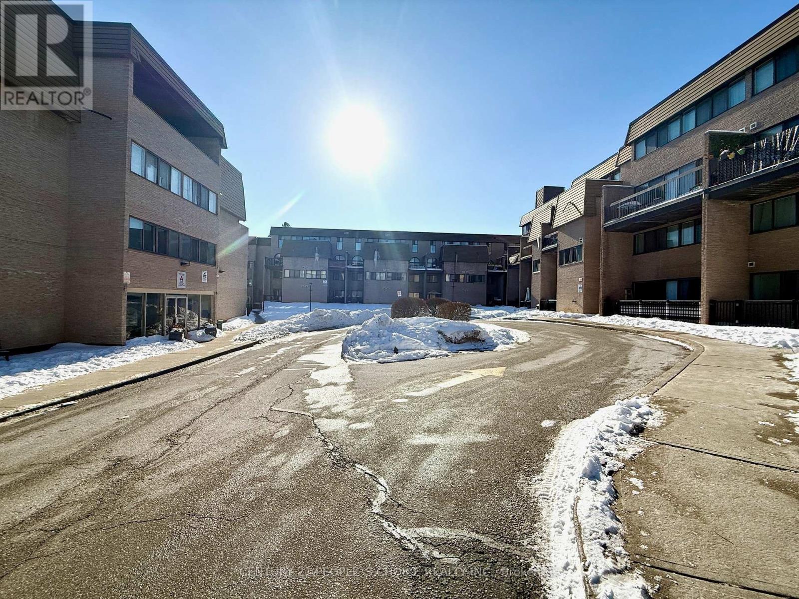 A sunny day in a snowy parking lot with buildings on either side.