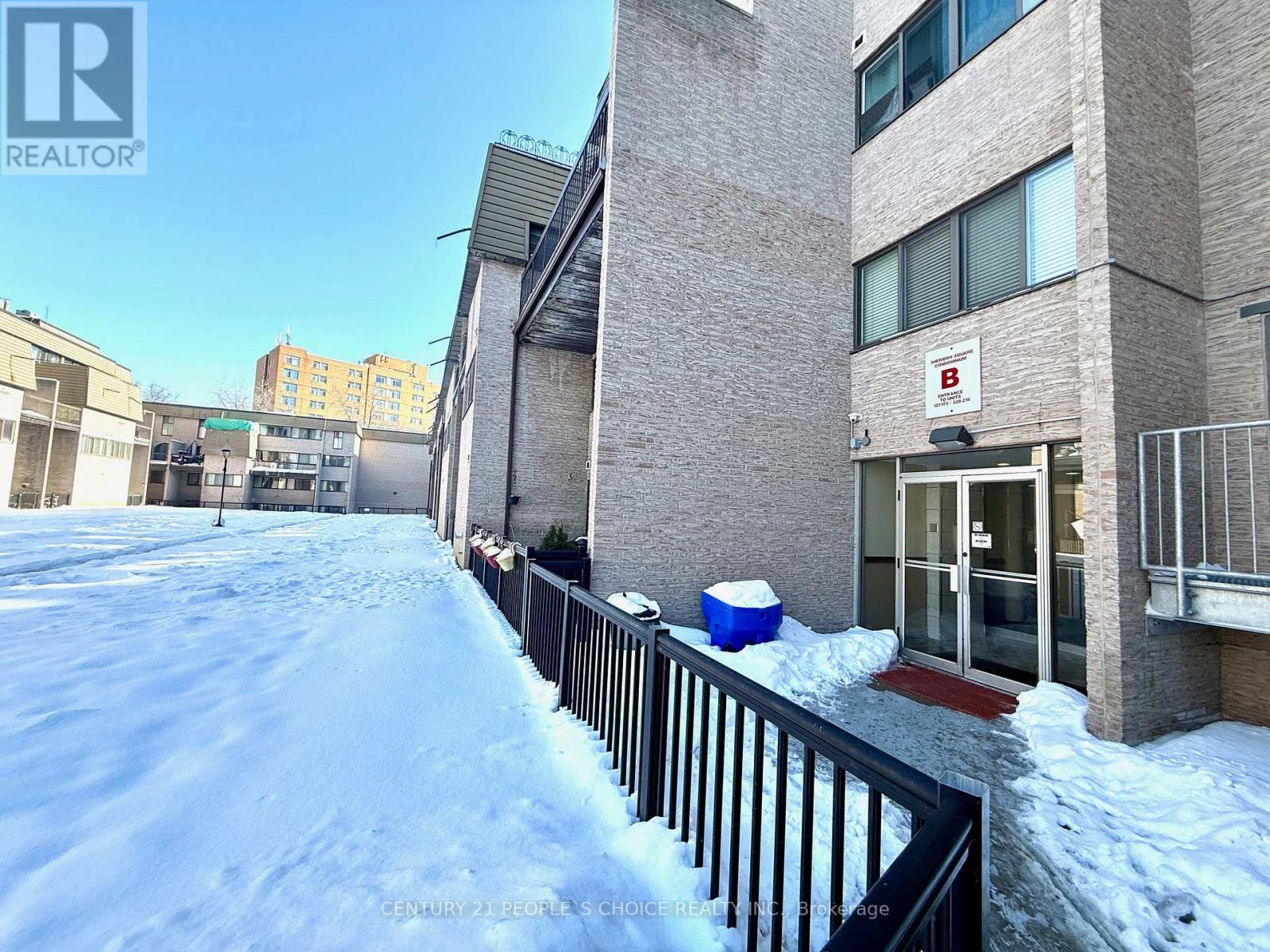 A snowy scene in front of a building with a sign that says "REALTOR".