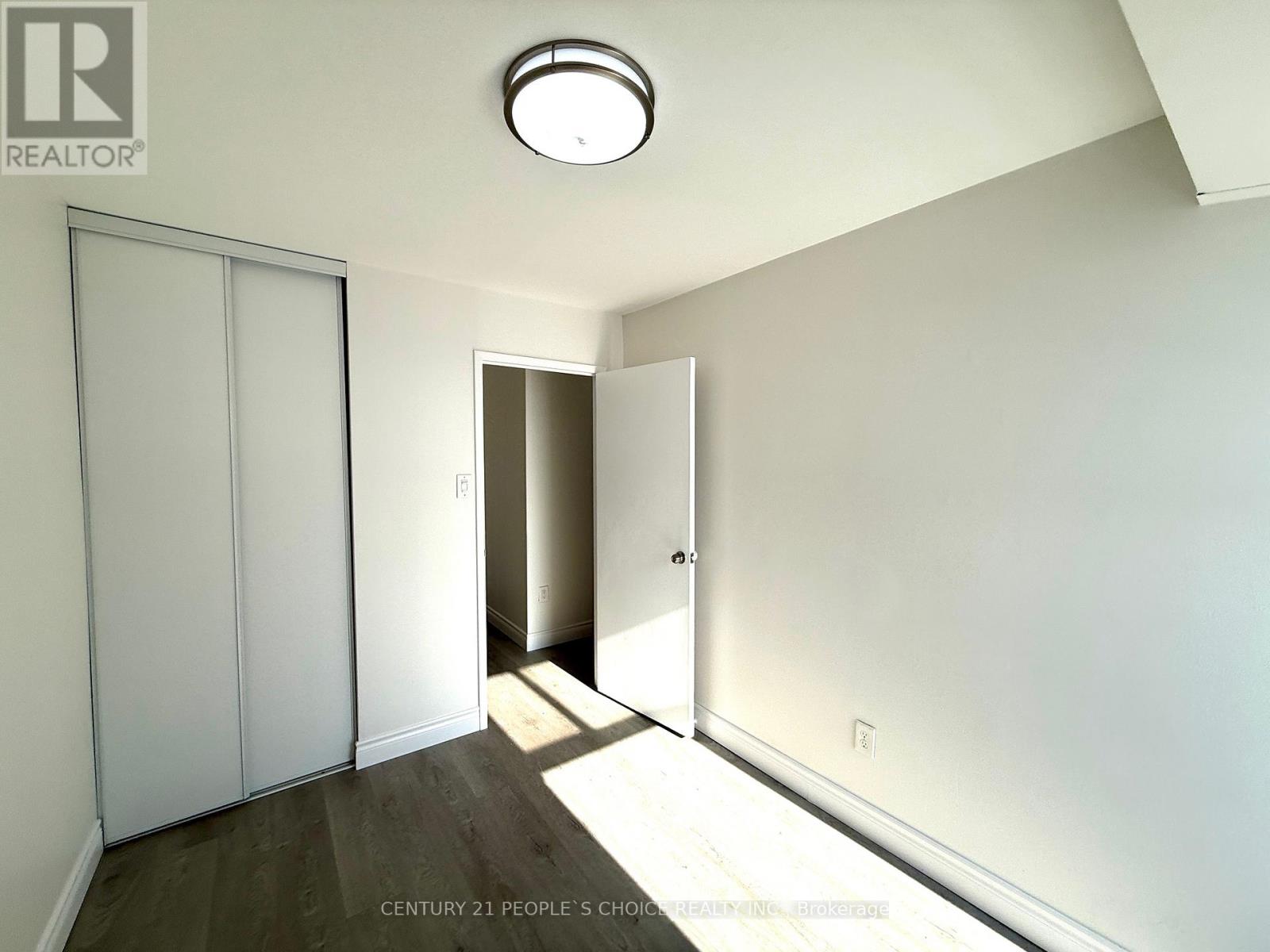 A white bedroom with a slanted ceiling and a light on the ceiling.