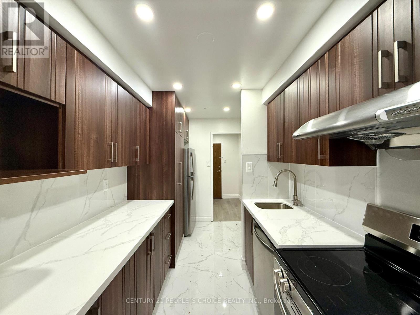 A kitchen with brown cabinets and white marble countertops.