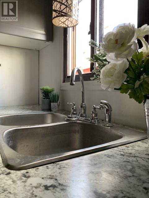 A modern kitchen with a stainless steel sink and a vase of white flowers.