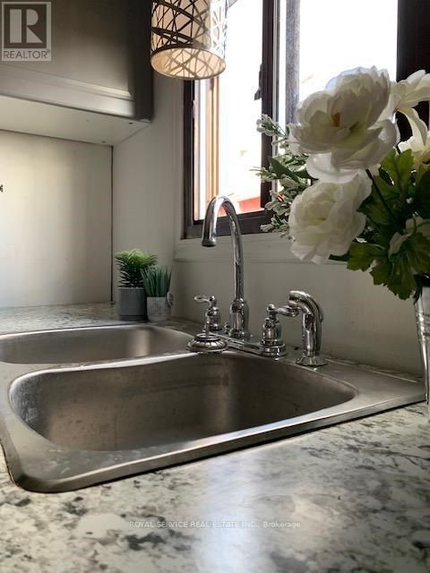 A modern kitchen with a stainless steel sink and a vase of white flowers.