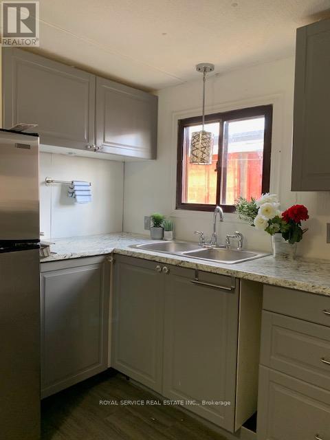A kitchen with a sink, refrigerator, and cabinets.