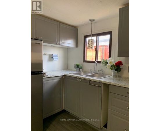 A kitchen with a sink, refrigerator, and cabinets.