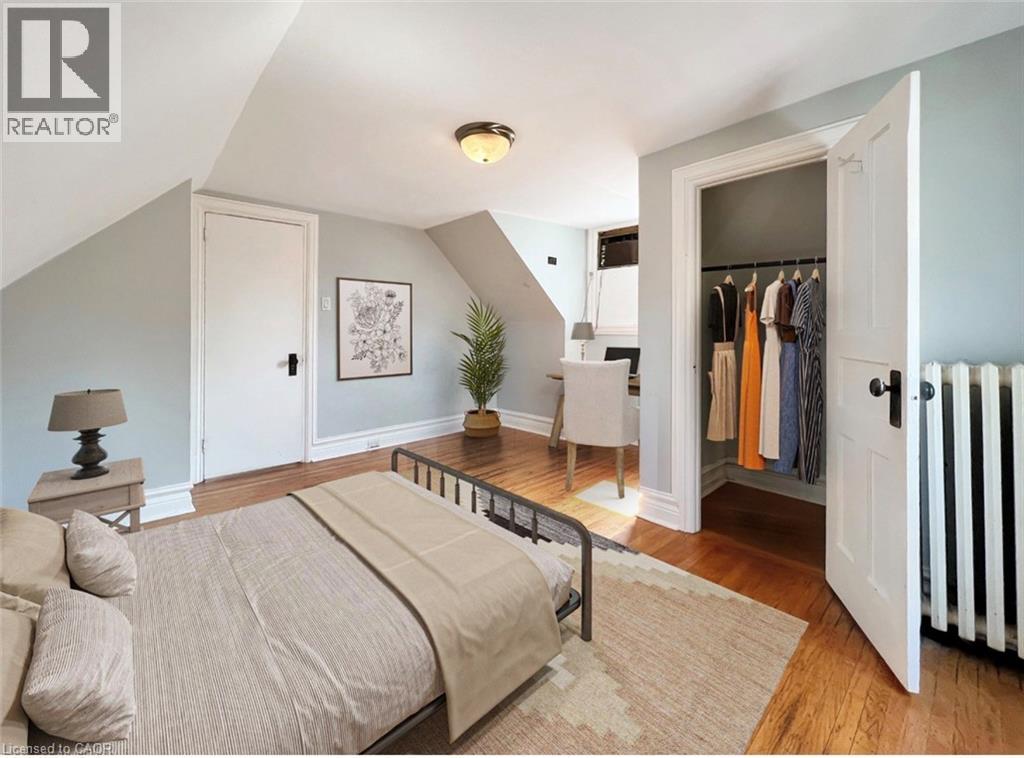 A bedroom with a bed, a side table with a lamp, a wardrobe, and a chair.