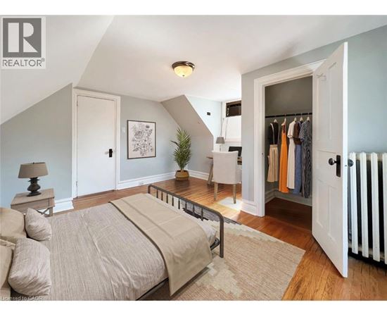 A bedroom with a bed, a side table with a lamp, a wardrobe, and a chair.