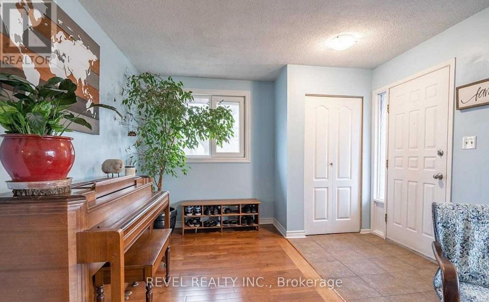 A living room with a piano, two doors, and a plant.