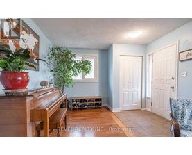 A living room with a piano, two doors, and a plant.