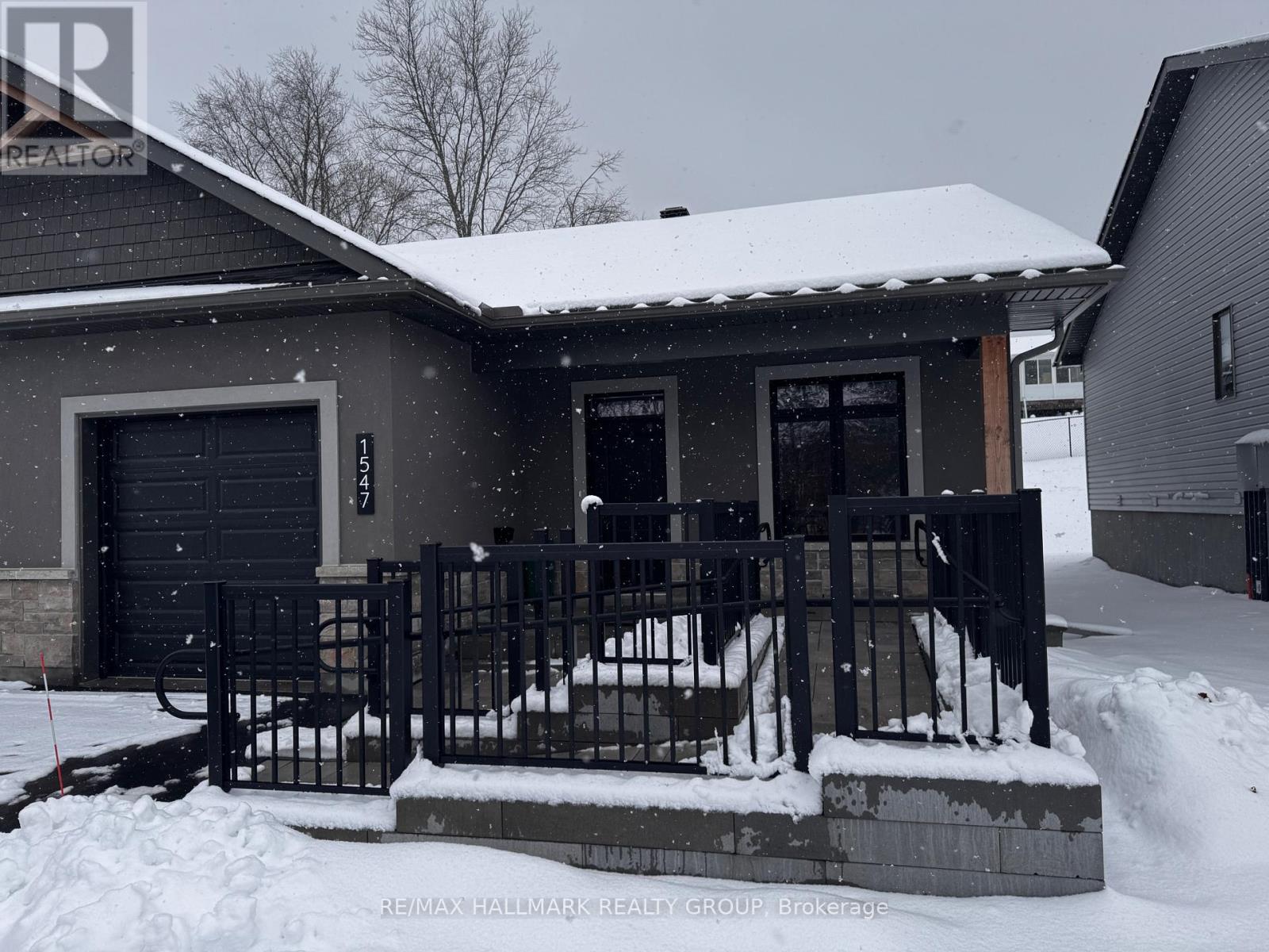 A house with a snow-covered front yard and a black fence.