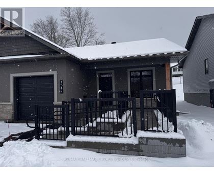 A house with a snow-covered front yard and a black fence.