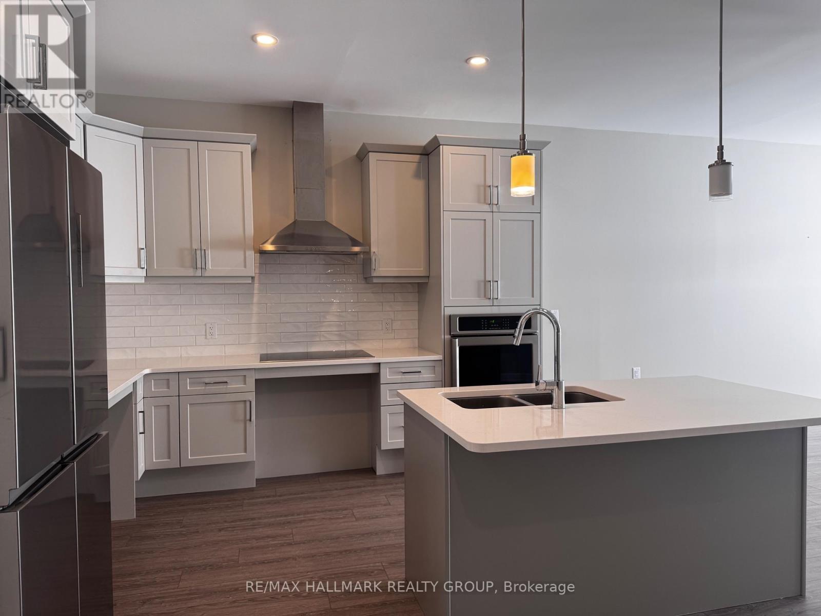 A kitchen with a refrigerator on the left and a sink with a stove top oven on the right.