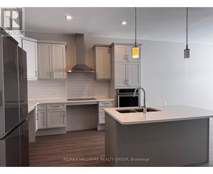A kitchen with a refrigerator on the left and a sink with a stove top oven on the right.