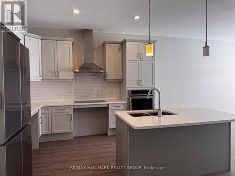 A kitchen with a refrigerator on the left and a sink with a stove top oven on the right.