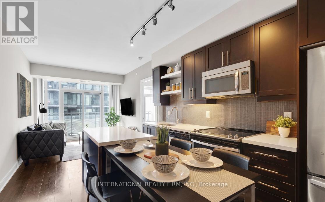 A modern kitchen with dark wood cabinets and stainless steel appliances.