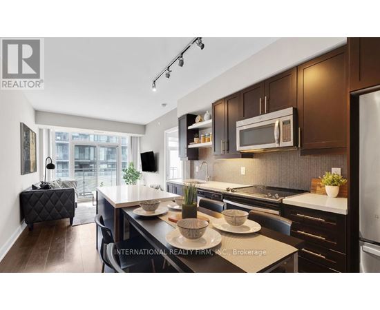 A modern kitchen with dark wood cabinets and stainless steel appliances.