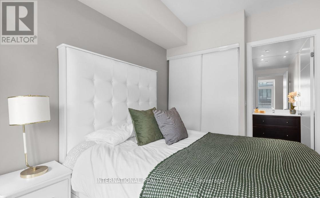 A bedroom with a white bed and a green and white bedspread.