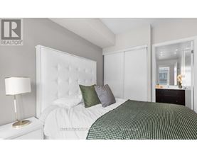 A bedroom with a white bed and a green and white bedspread.