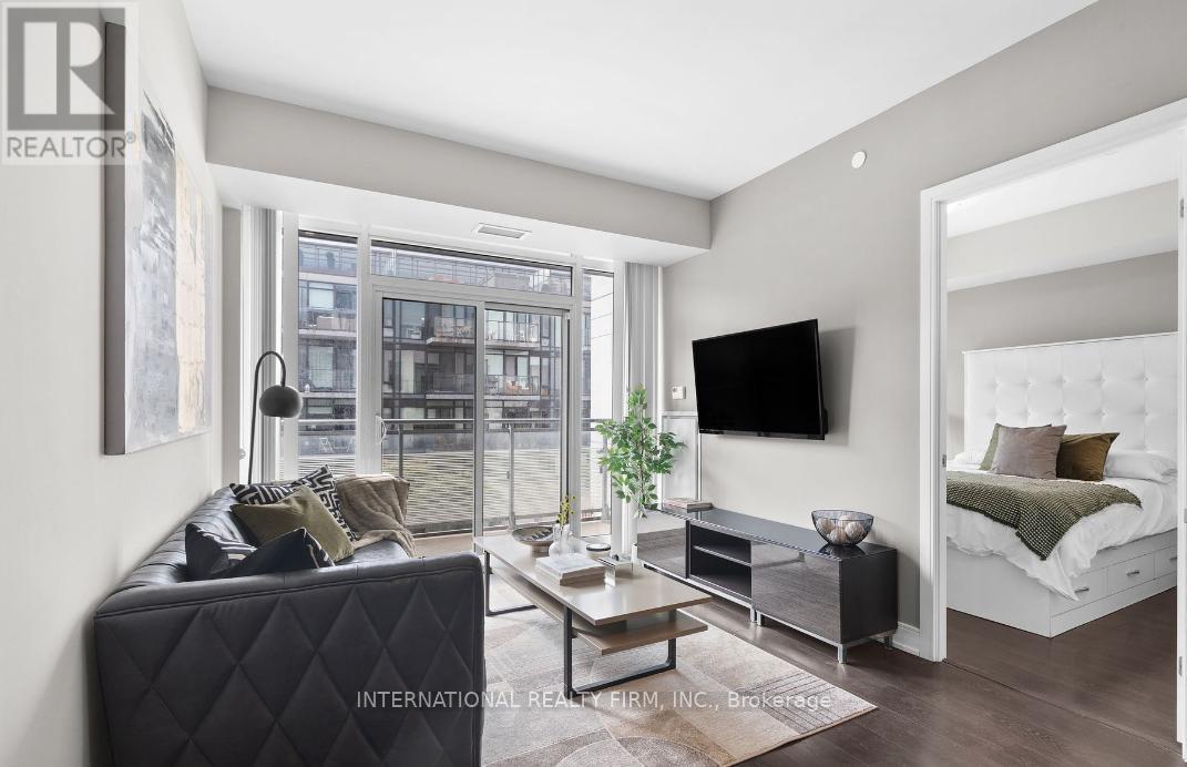 A modern living room with a black leather sofa and a flat screen TV mounted on the wall.