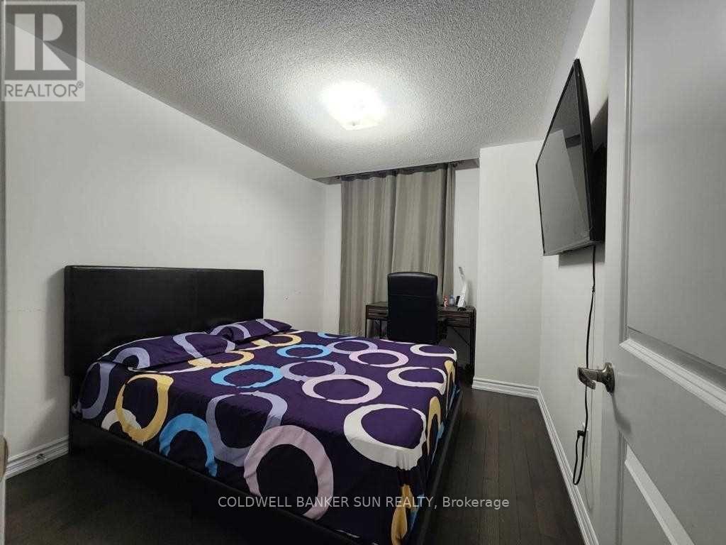 A bedroom with a bed, a television, and a window with curtains.