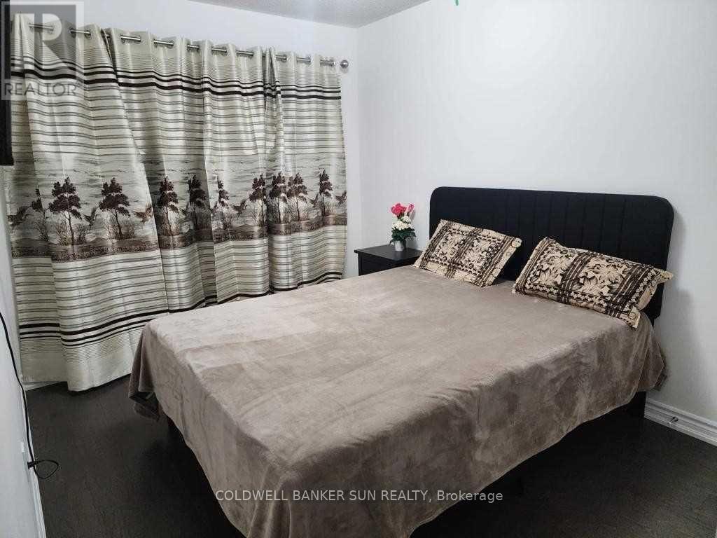 A bedroom with a bed, pillows, and a curtain with a floral pattern.