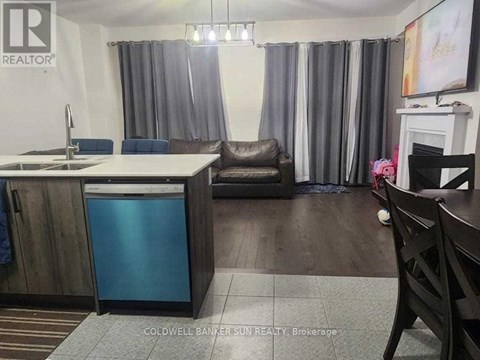 A kitchen with a sink, a fridge, a chair and a table.