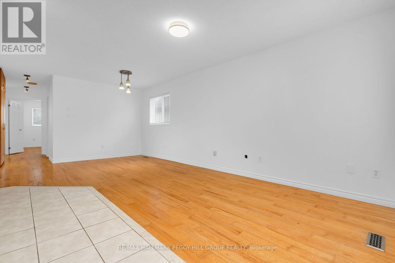 A spacious room with wooden flooring and white walls.