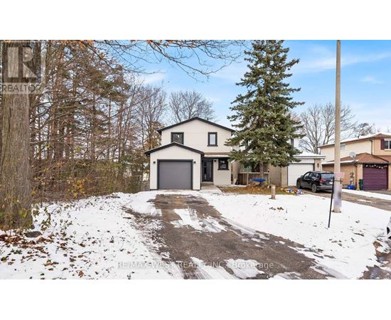 A house with a garage is surrounded by snow and trees.