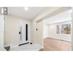 A room with a white door and a window with a view of trees outside.