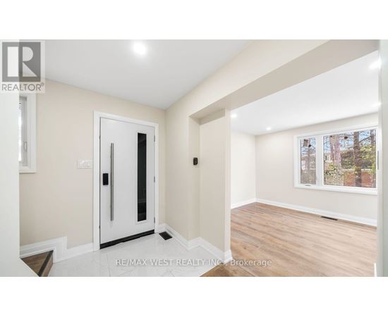 A room with a white door and a window with a view of trees outside.