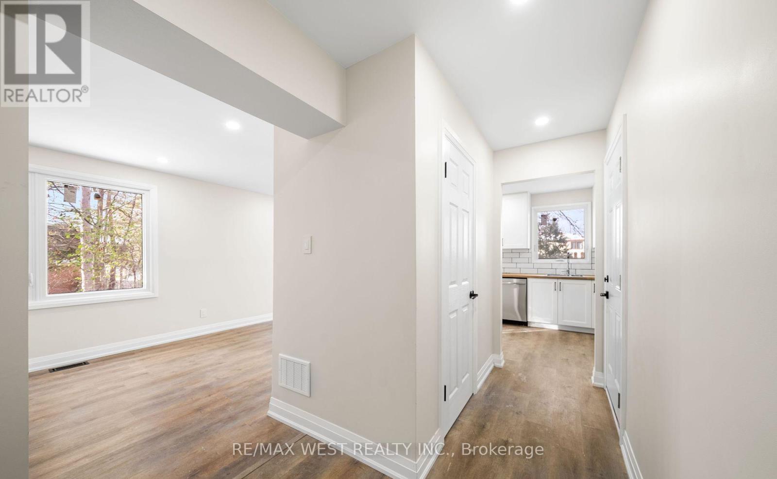 A spacious room with a view of a tree-lined street through a window.
