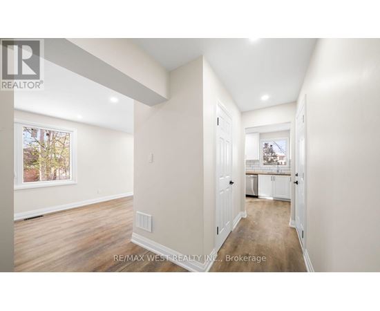 A spacious room with a view of a tree-lined street through a window.
