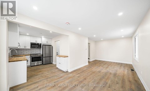 A spacious kitchen with white cabinets and a wooden countertop.