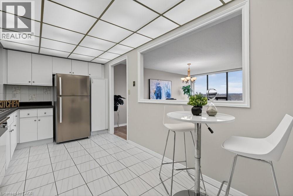 A kitchen area with a refrigerator, a dining table with two chairs, and a window with a view of the outdoors.