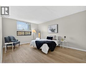 A bedroom with a bed, chair, and painting on the wall.