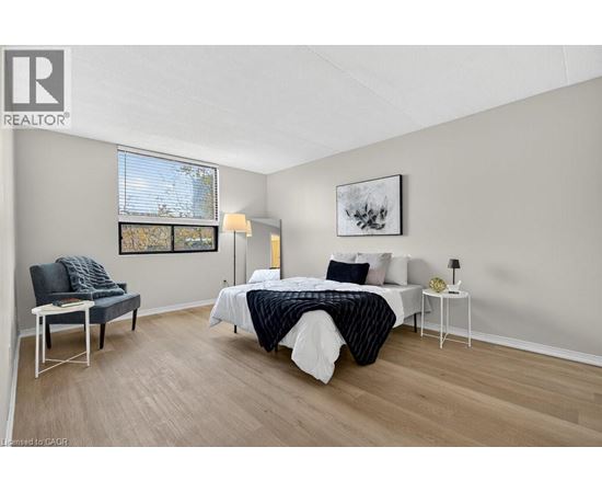 A bedroom with a bed, chair, and painting on the wall.