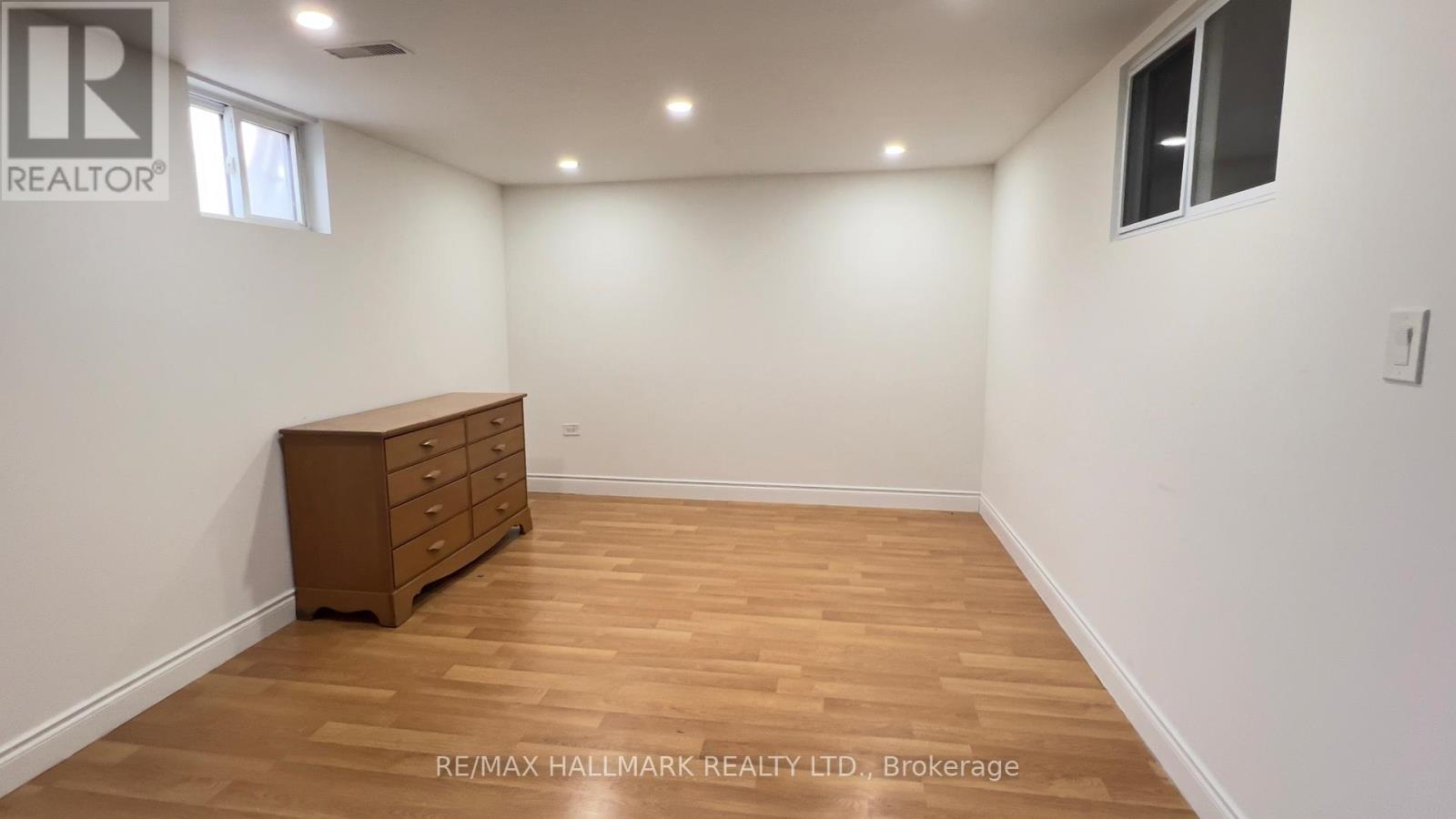 A room with a wooden floor and a brown dresser.