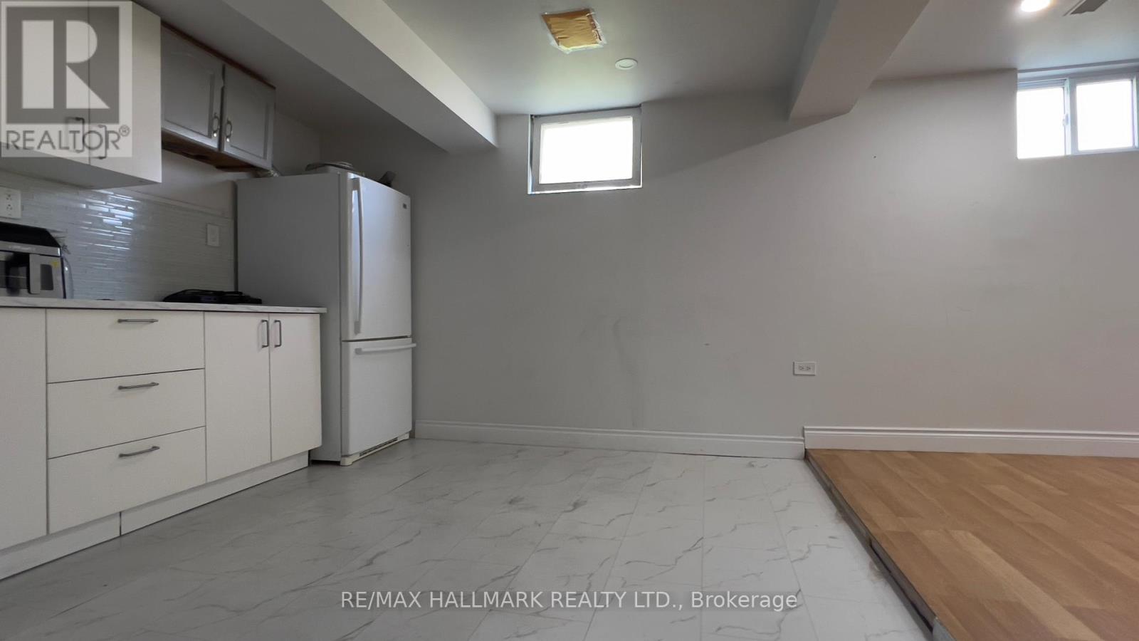 A kitchen with white cabinets and a refrigerator is shown.