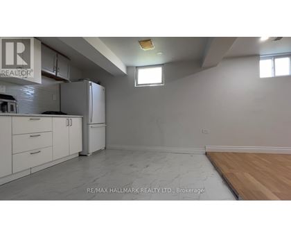 A kitchen with white cabinets and a refrigerator is shown.