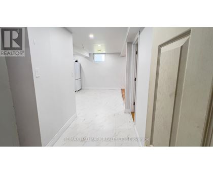 A white hallway with a door on the right and a window in the middle of the wall.