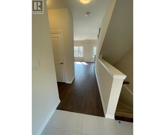 A hallway with a staircase and a door leading to another room.